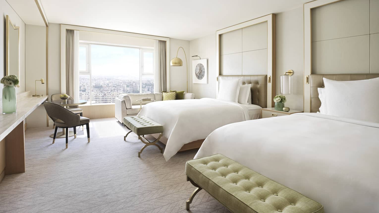 Bedroom with two plush twin beds, each with light green ottoman. Large window and arm chair.