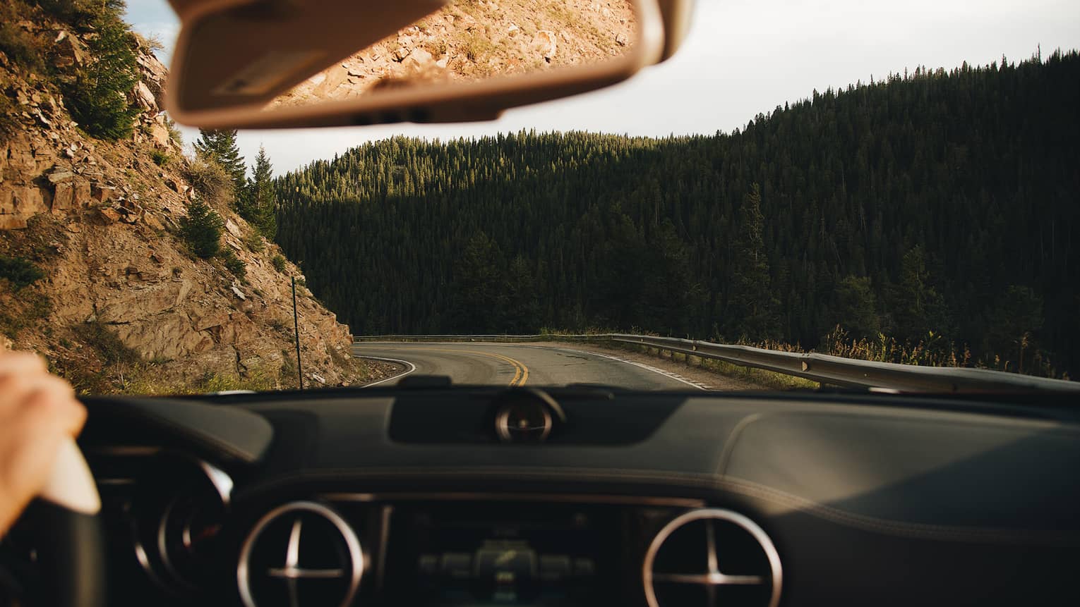 View from behind the wheel of car driving along winding mountain road 
