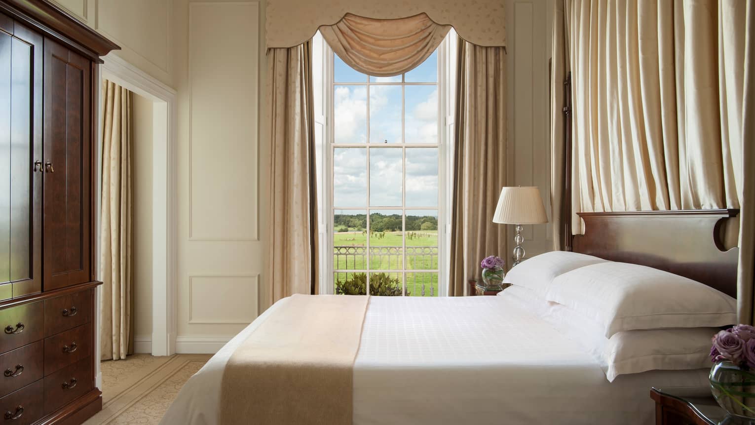 William Godson Suite tall window with canopy, bed by large wood wardrobe