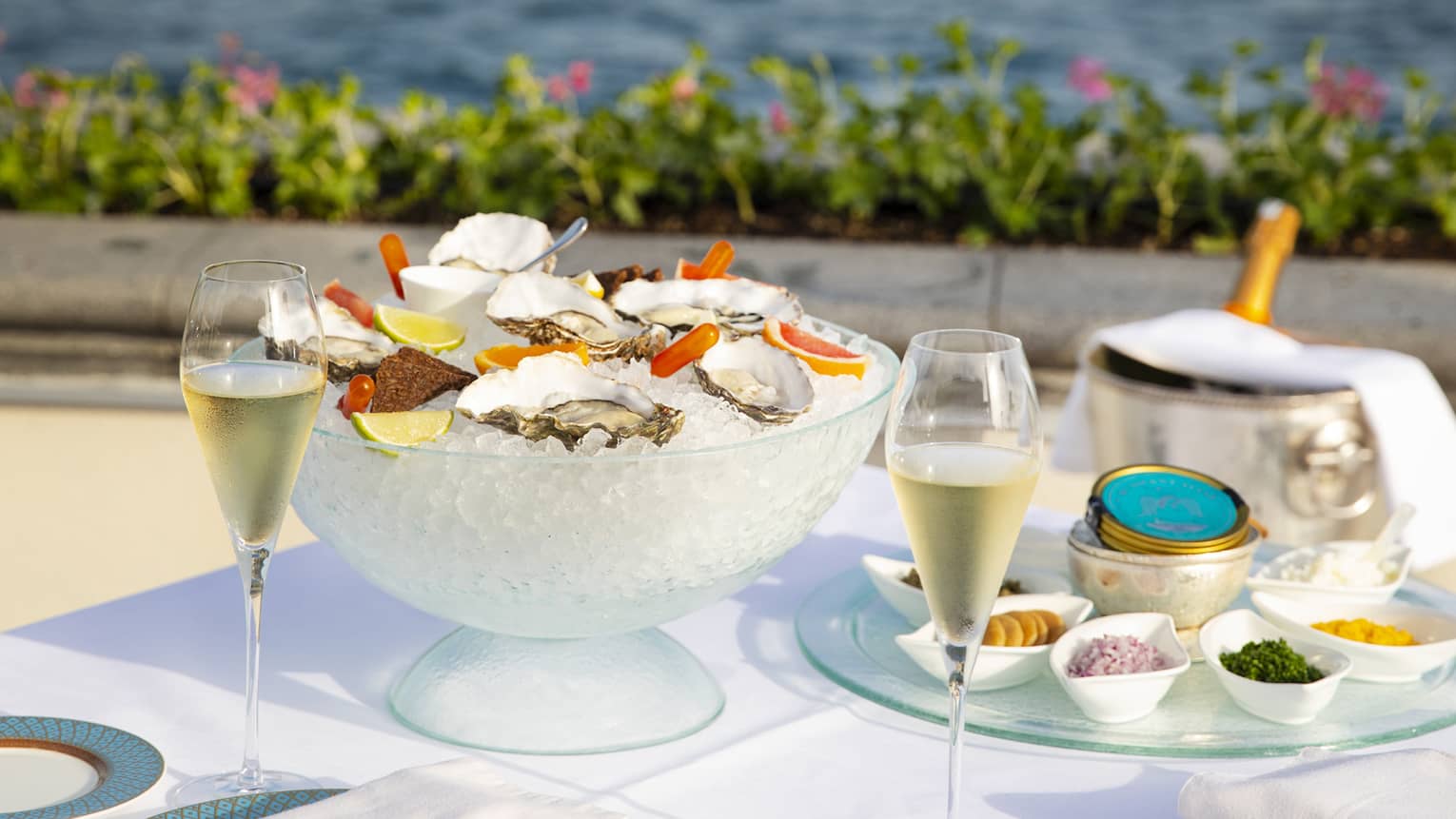 Square table with white linens, blue dinnerware, a bowl of ice with oysters on the half shell, Sea of Marmara in the background