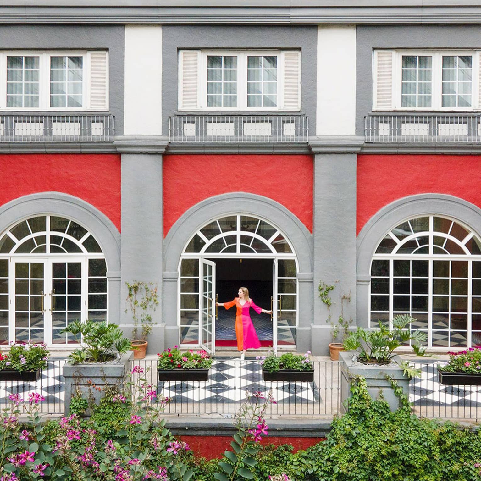 View over patio with arched glass doorways, woman wearing colourful dress 