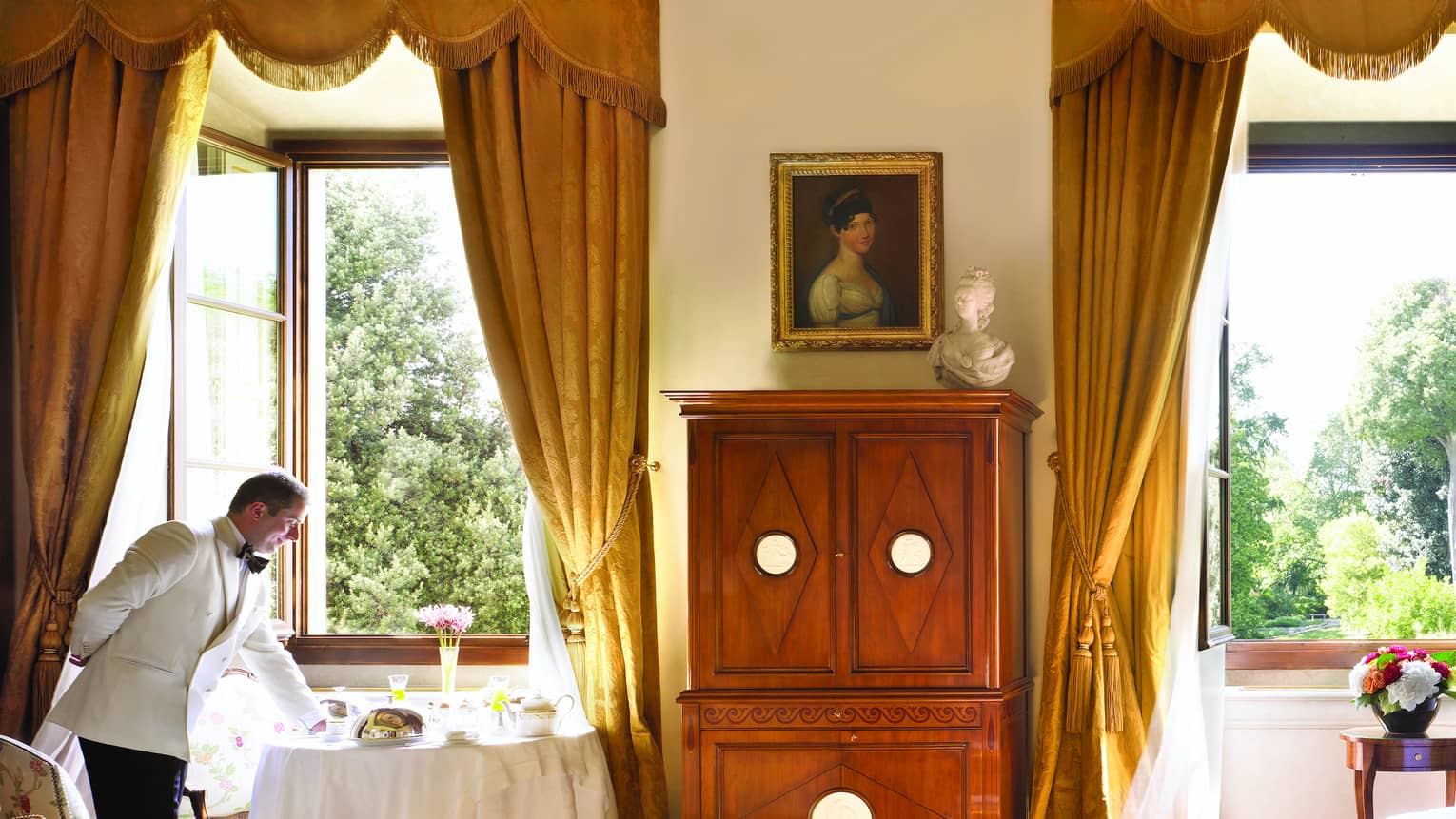 Hotel staff sets in-room dining table by large window in sunny Renaissance Suite