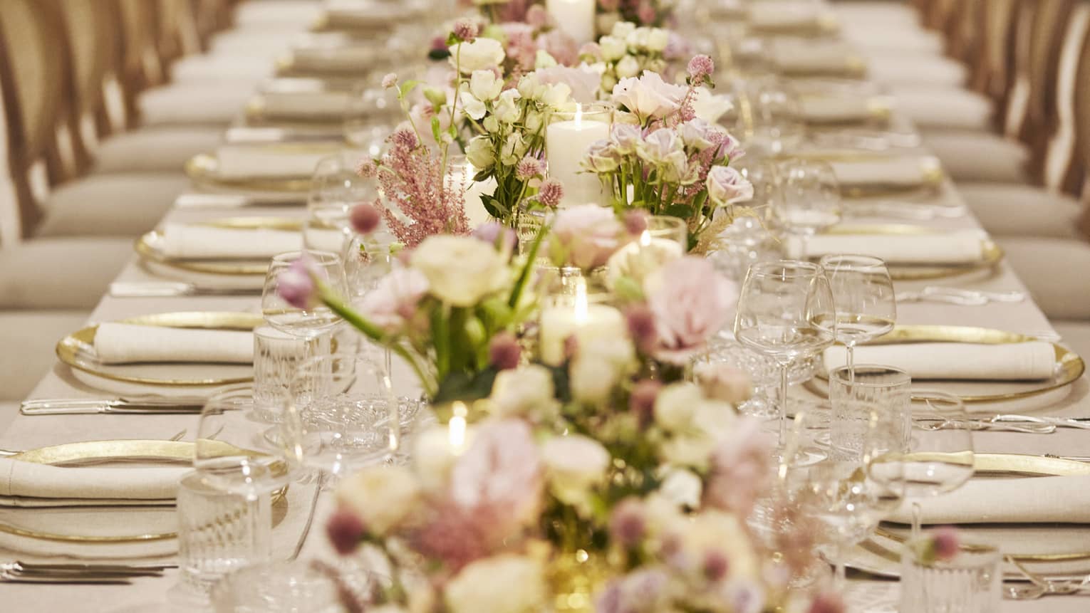 Elegantly set formal dining table with pink and white floral arrangements down centre