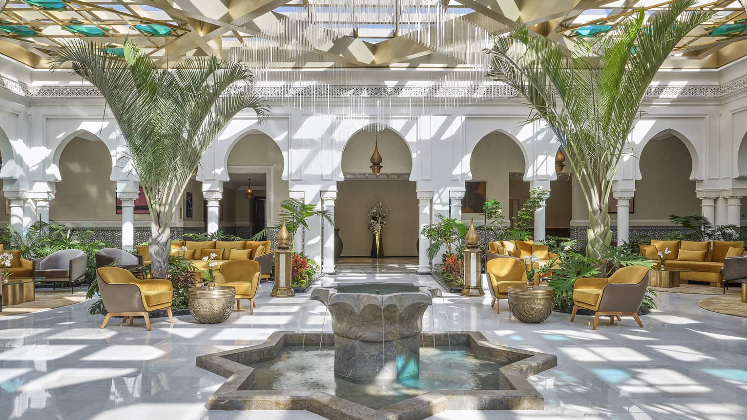 Light-filled lobby with glass ceiling, lounge seating and fountain at Four Seasons Hotel Rabat