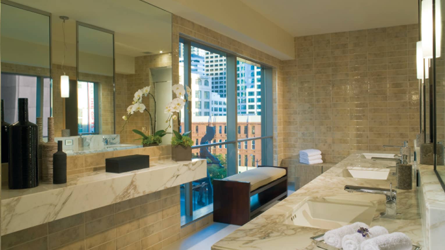 Marble sinks, rolled white towels in front of spa window