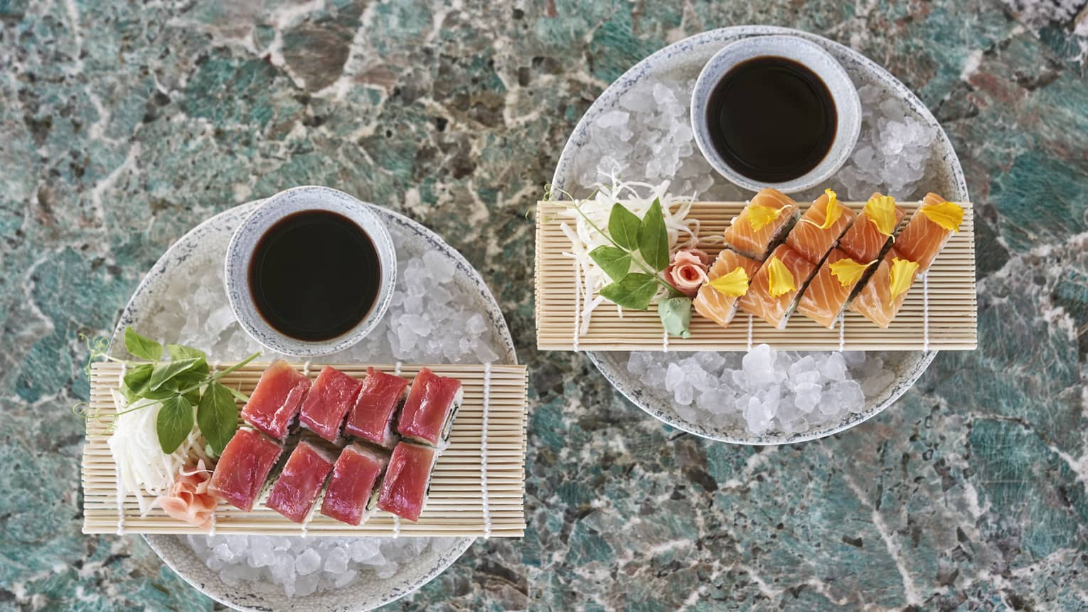 Two plates of sushi resting over ice.