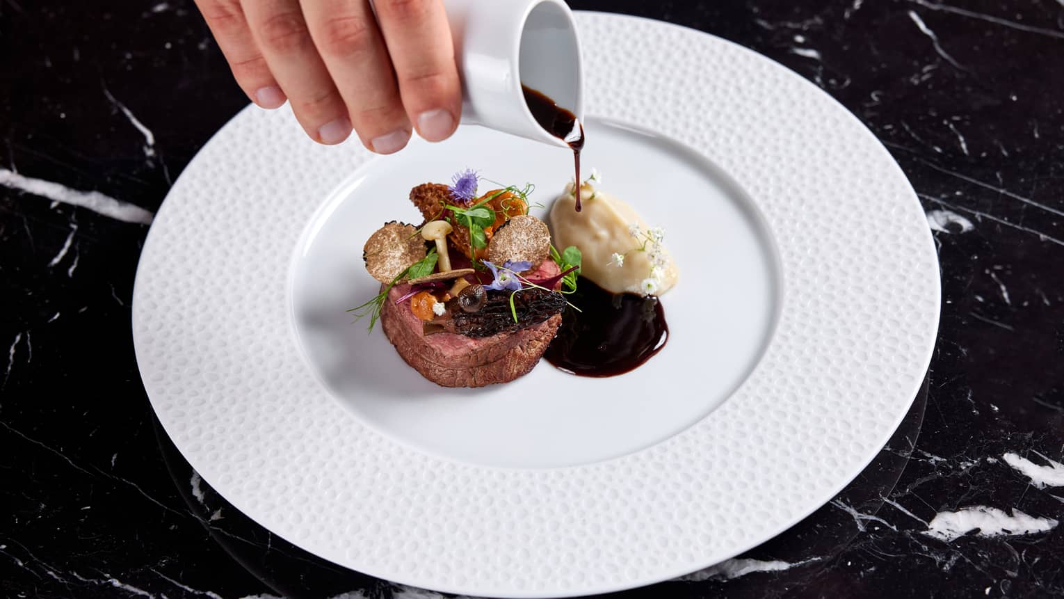 Beef tenderloin and a dark sauce on a white plate.