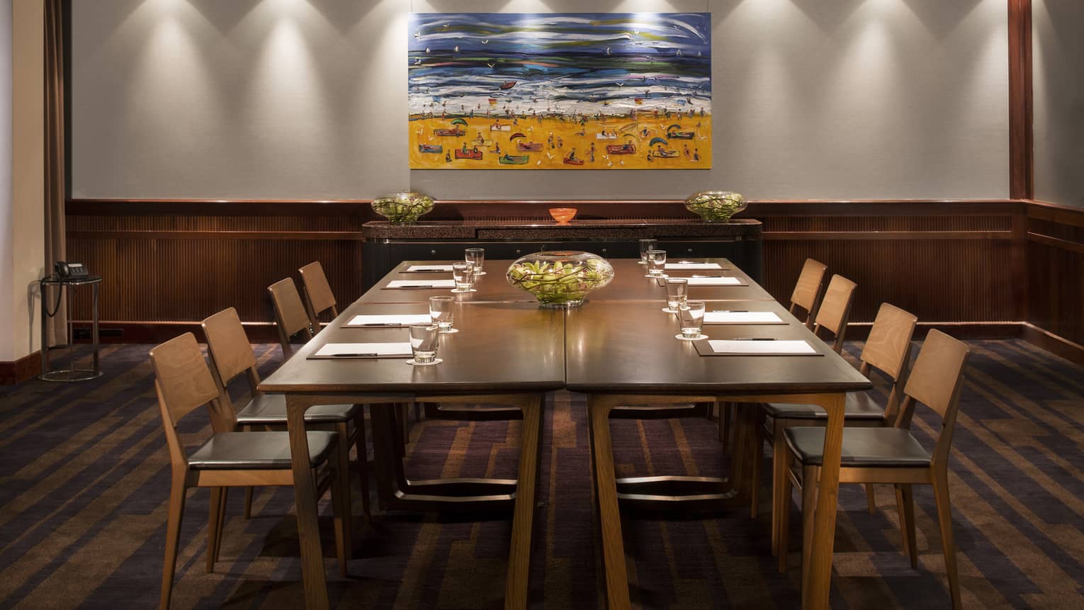 Gallery meeting room with large boardroom table, retro-style chairs under colourful painting of beach