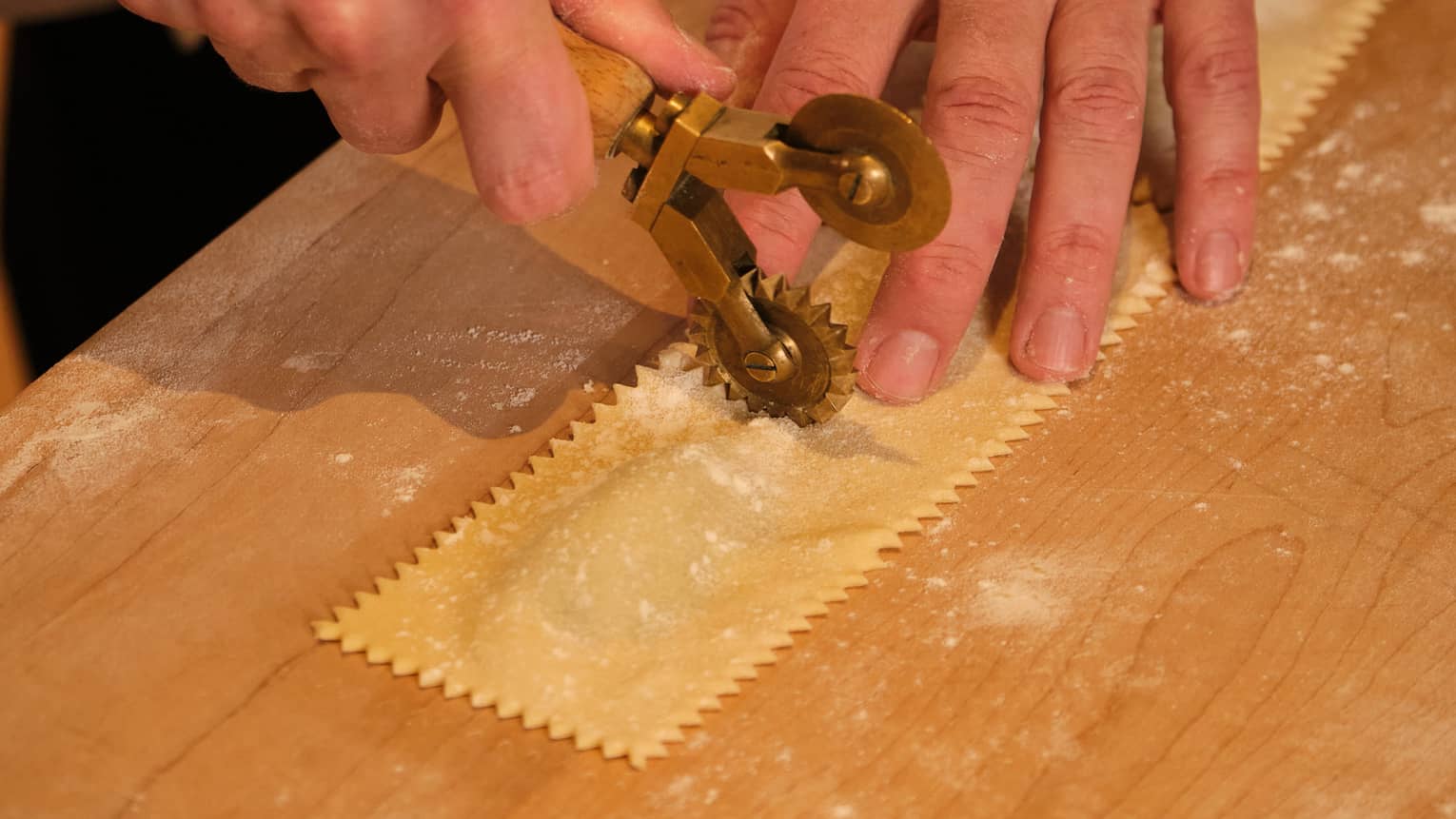 A chef crimping a sheet of ravioli pasta