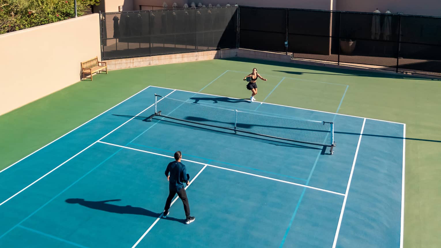 Aerial view of two guests playing a game of tennis.