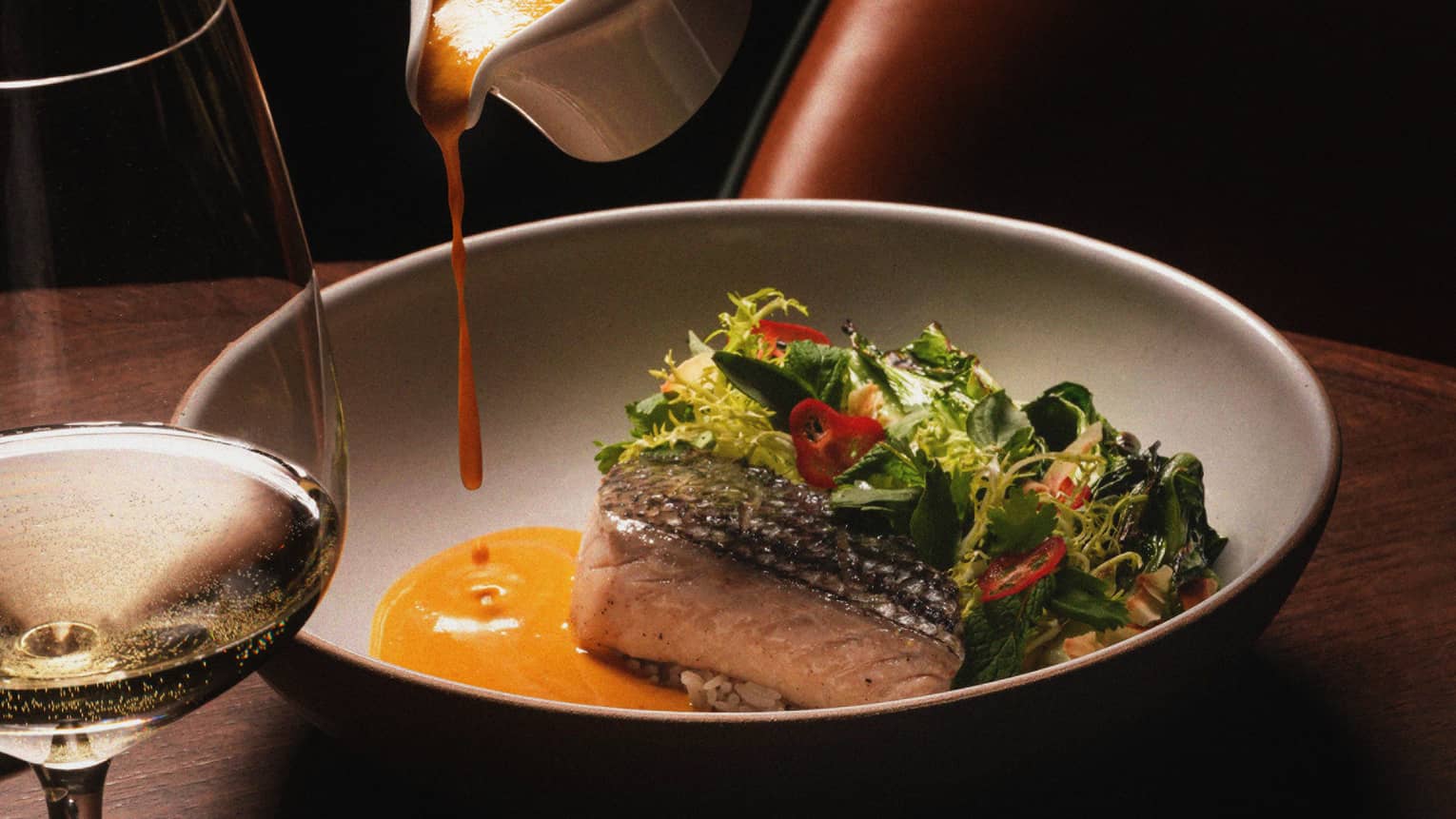 Black bass in a wide bowl with vegetables and coconut-curry sauce