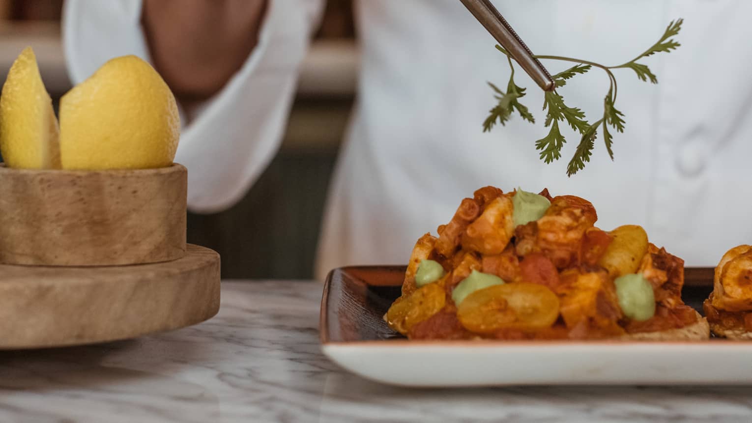 A chef picking up an herb with a utensil.