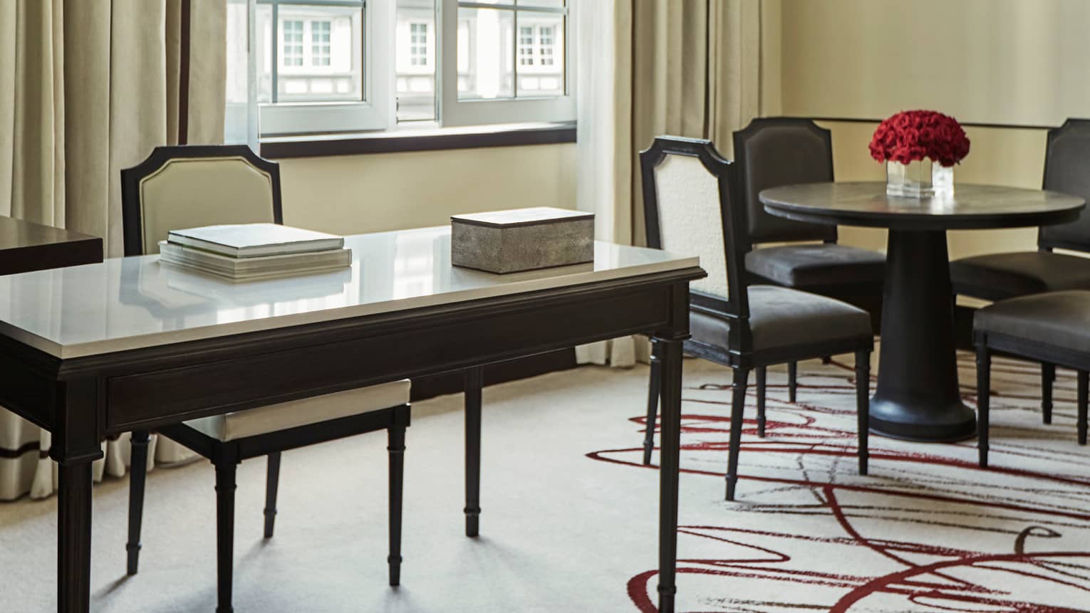 Hotel suite modern white desk, chair with books by cafe dining table with red roses, sunny window