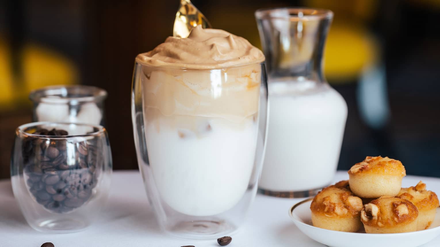 A person stirs a caffe latte with gold spoon