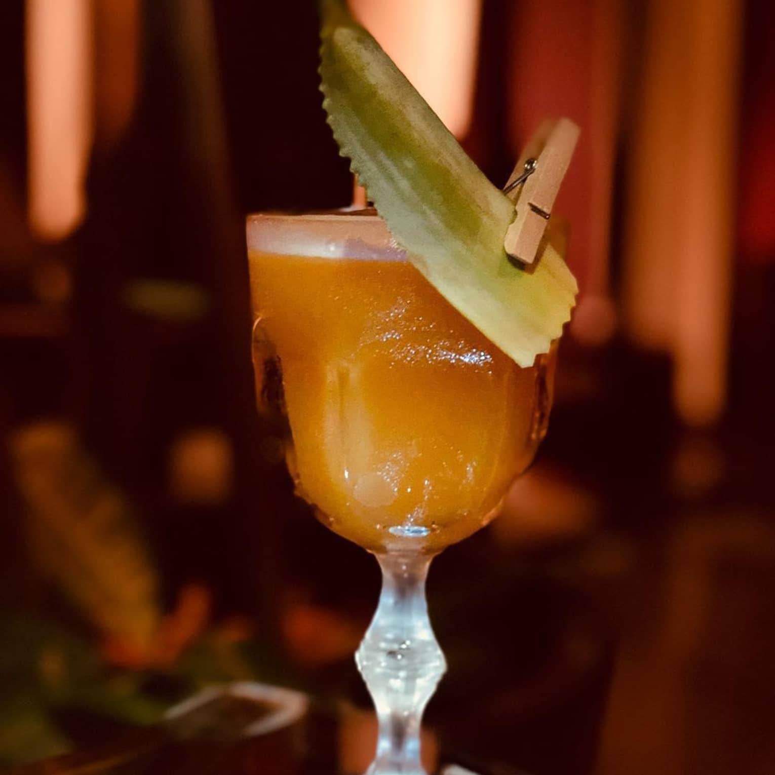 A chilled orange cocktail served with a leafy garnish
