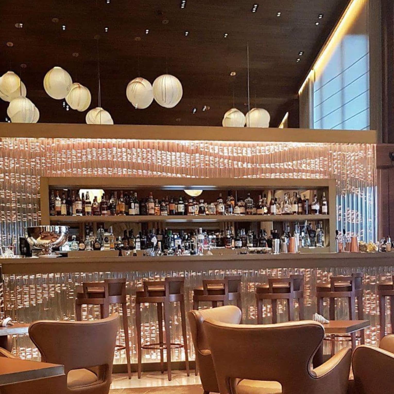 Stools at glass bar, mid-century style lounge chairs