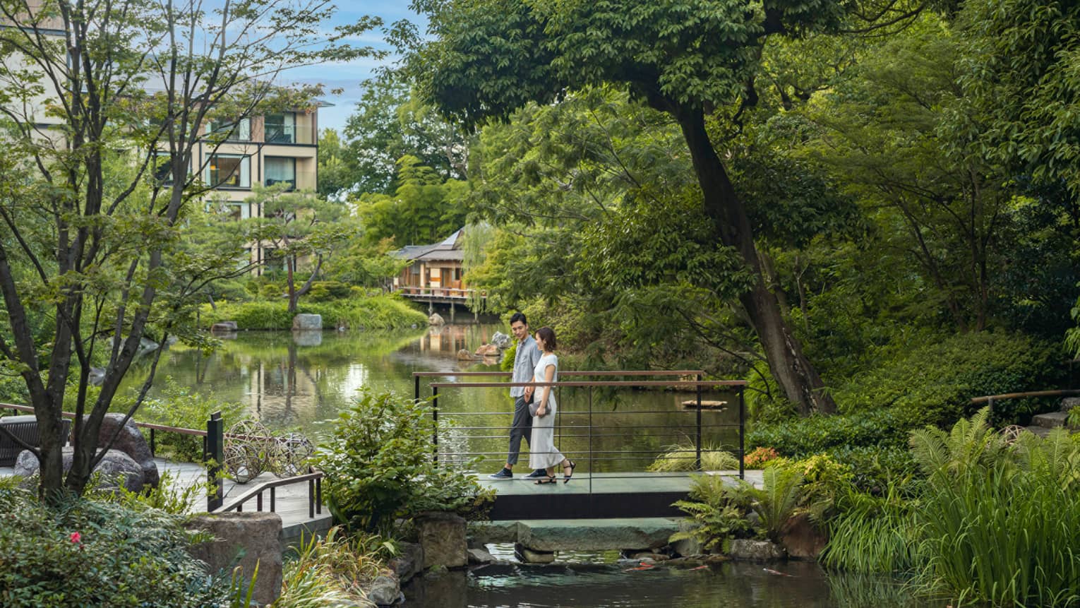 Couple walks across foot bridge over koi pond