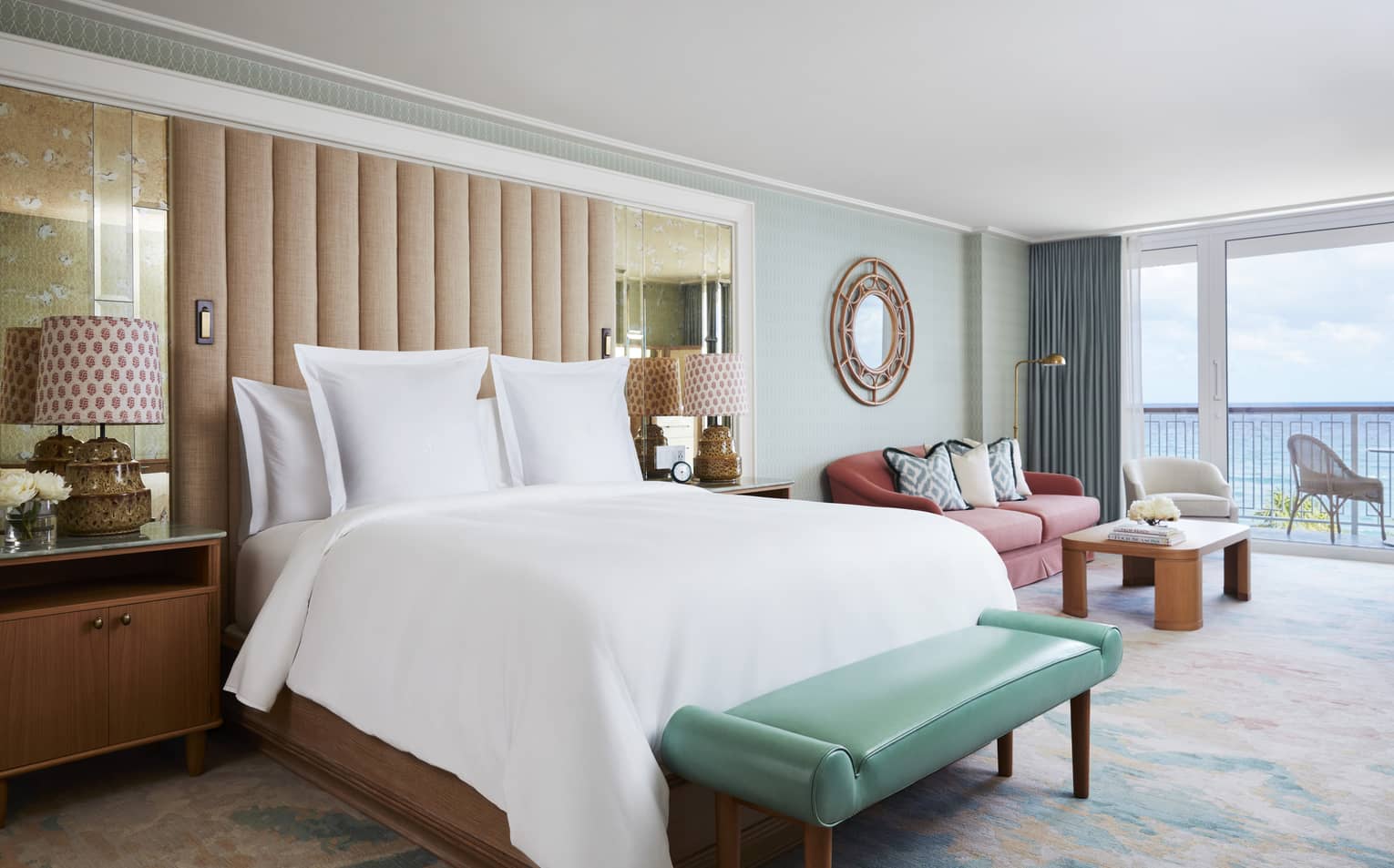 Ocean View Studio Suite bed and teal leather bench by seating area, balcony door