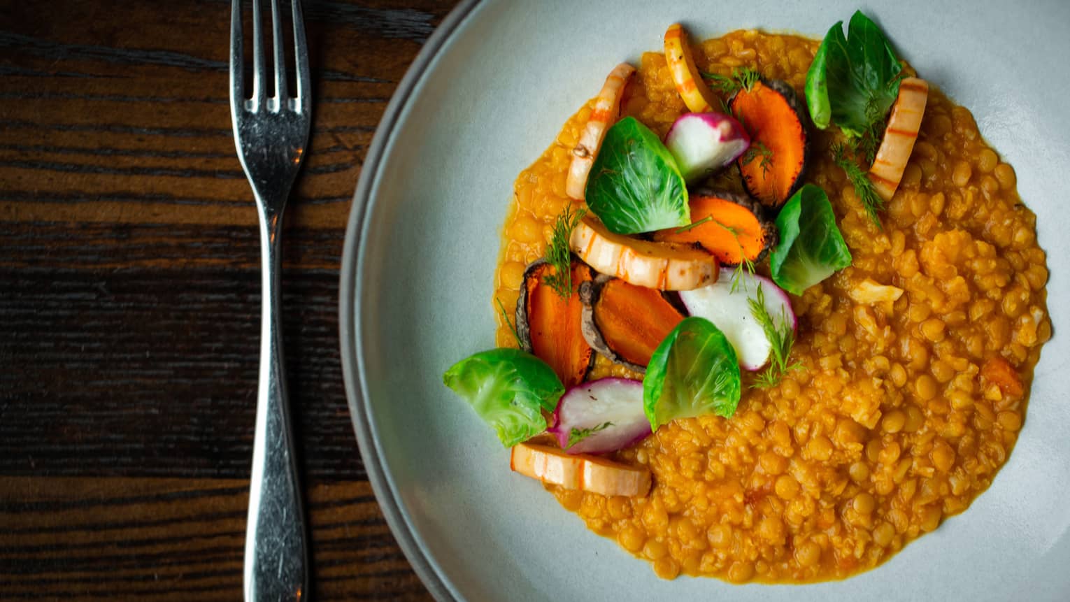 A plate of red lentils garnished with a colorful array of vegetables.