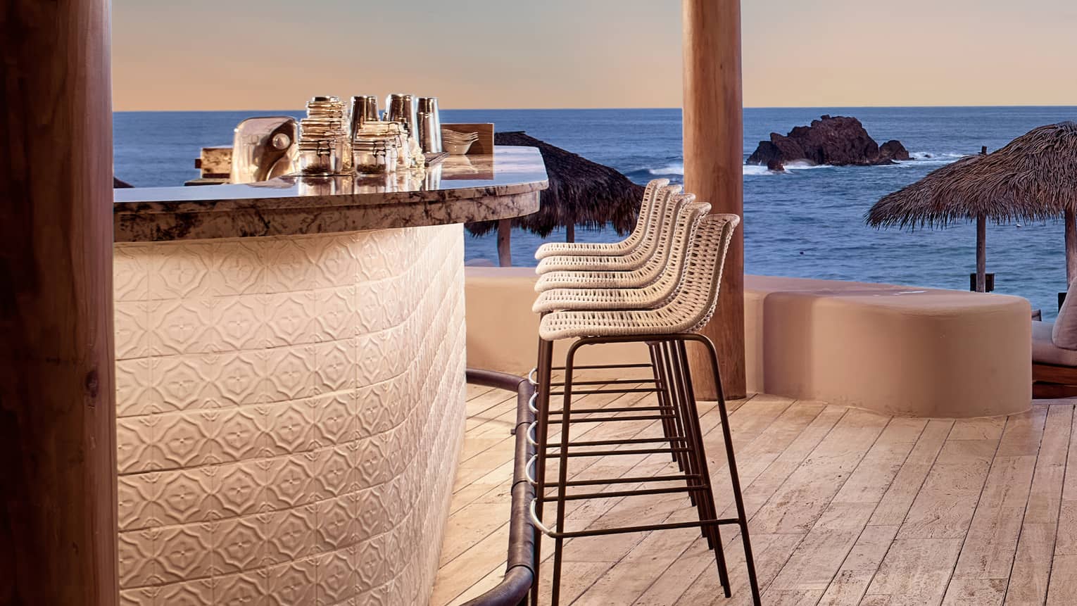 A bar with stools next to the ocean.