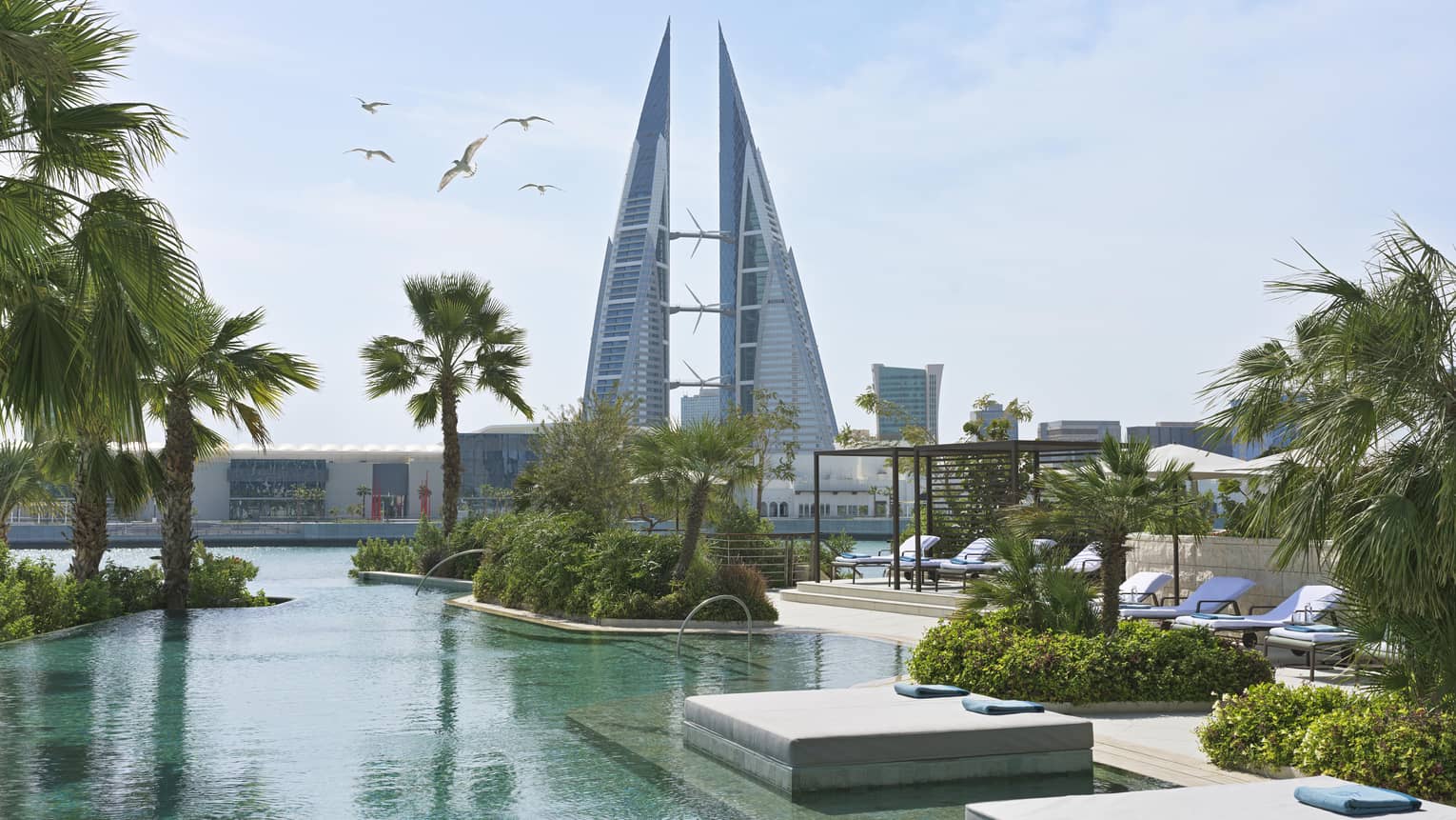 View of pool, loungers and buildings