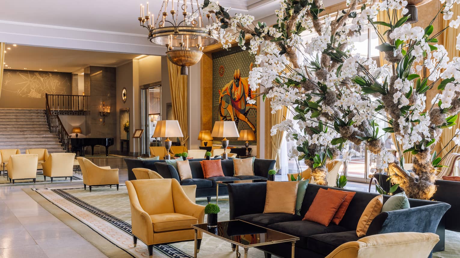 A lobby area with sofas, chairs and white flowers.
