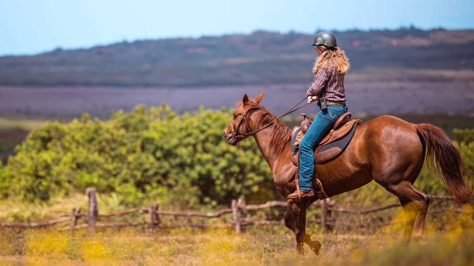 A woman horseback riding in a mountain landscape