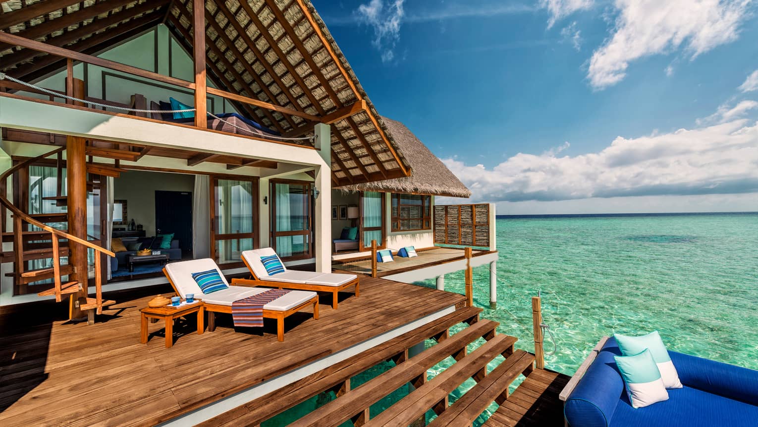 Lounge chairs by open bedroom door on Sunrise Water Villa sundeck tiered patio
