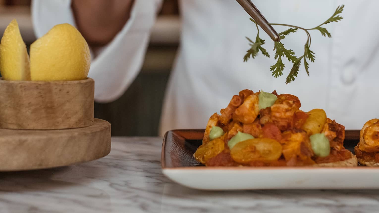 A chef picking up an herb with a utensil.
