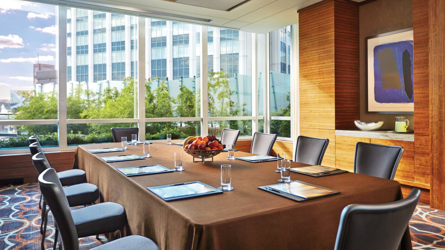 Large rectangular boardroom meeting table by bright floor-to-ceiling window