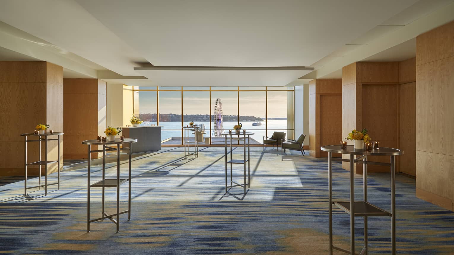 A foyer with standing tables and large windows on one wall.