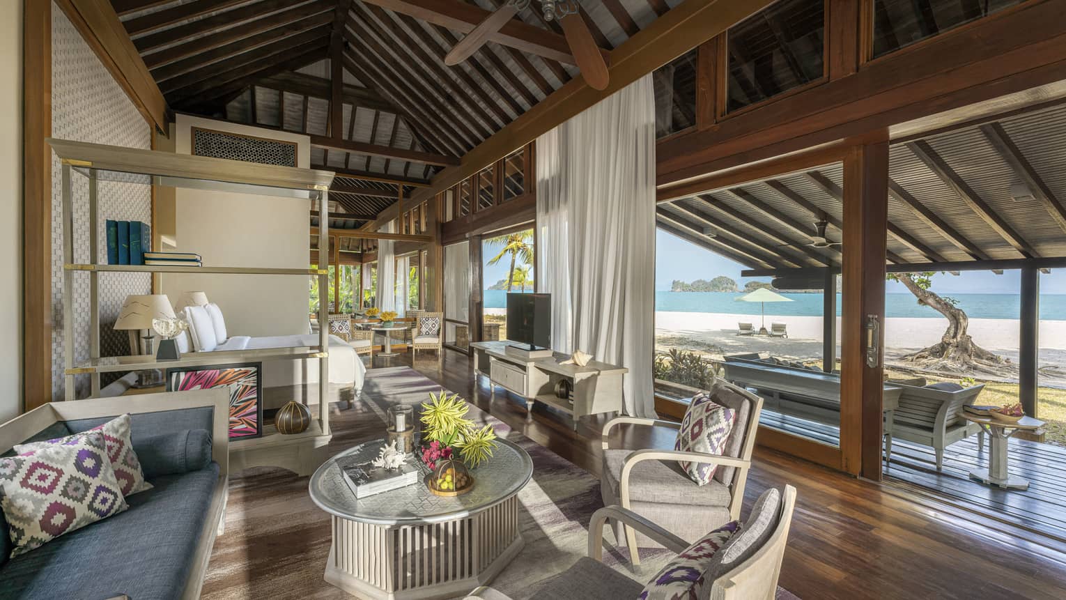 Teak living room opening to covered terrace with beach view