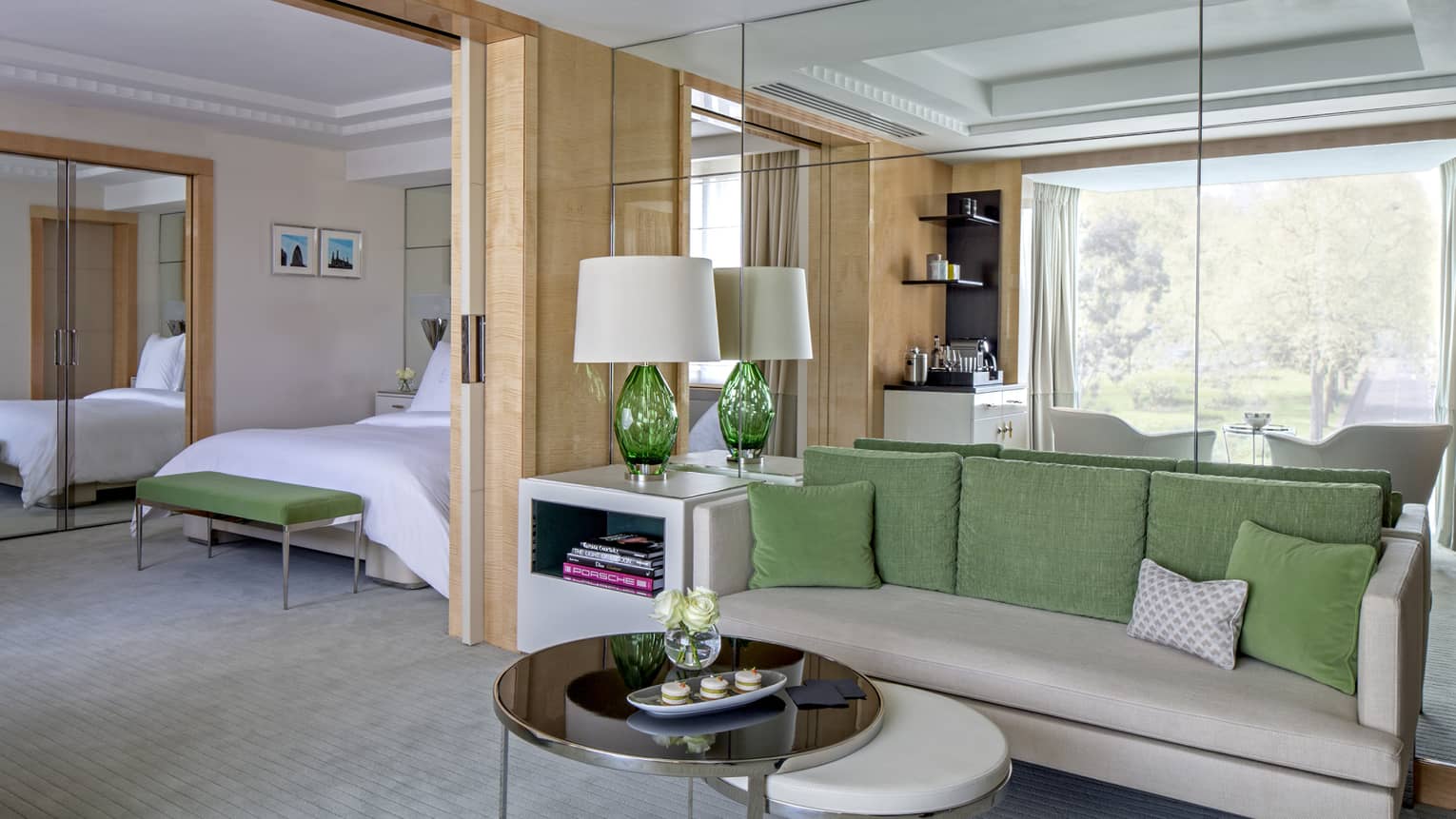 Mayfair Suite grey sofa with green pillows, round tables, alcove with bed, mirror