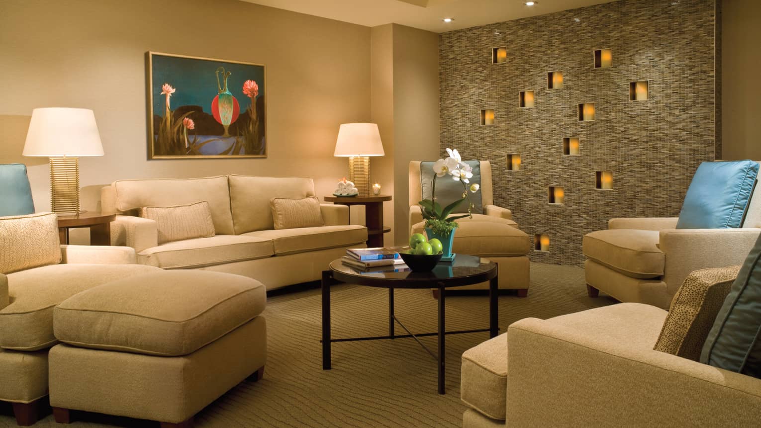 Large plush sofas, glowing candles in tile wall in spa lounge area