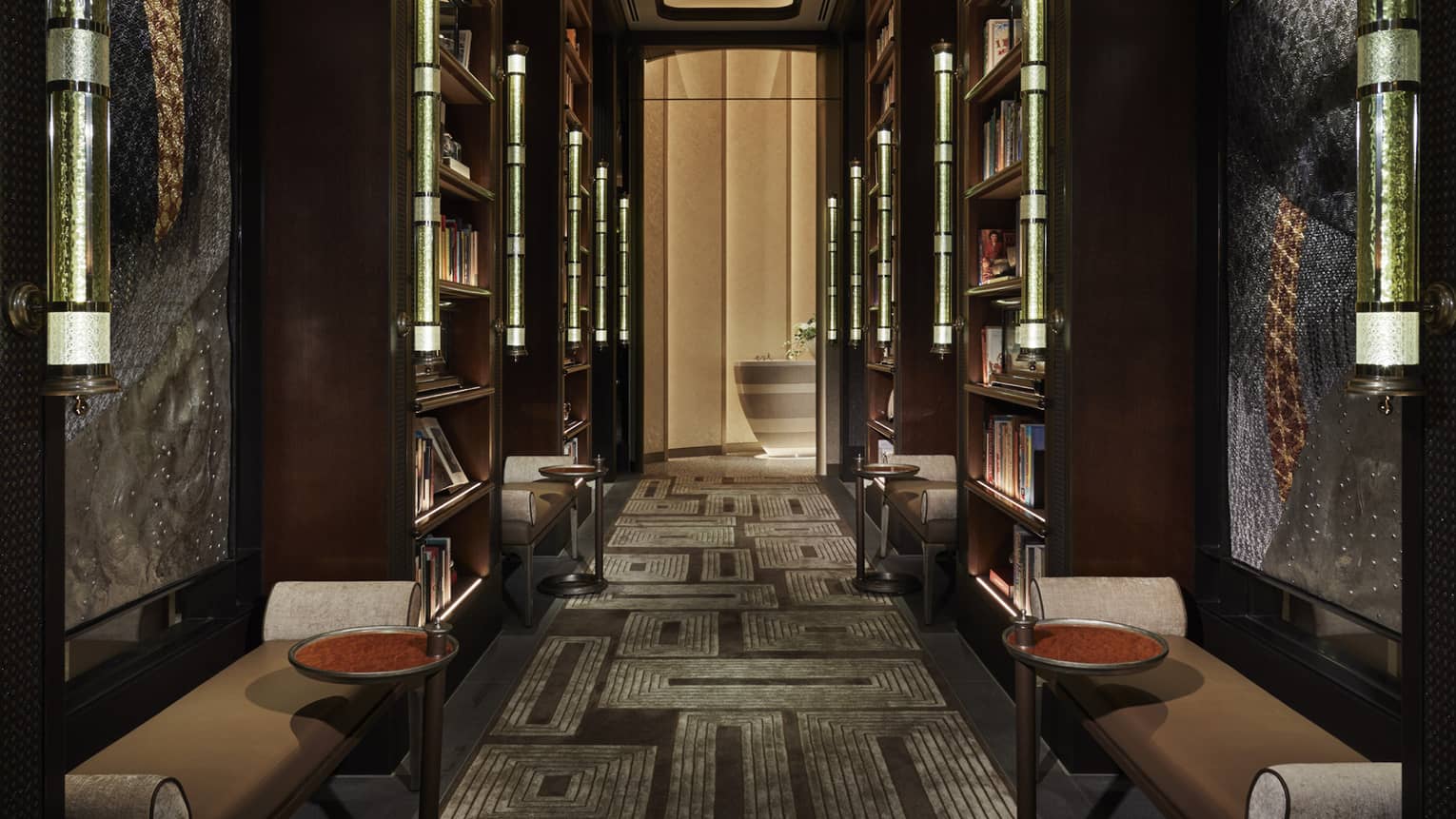 Hallway of Virtu, lowlighting, patterned carpet, plush chaise lounges on either side