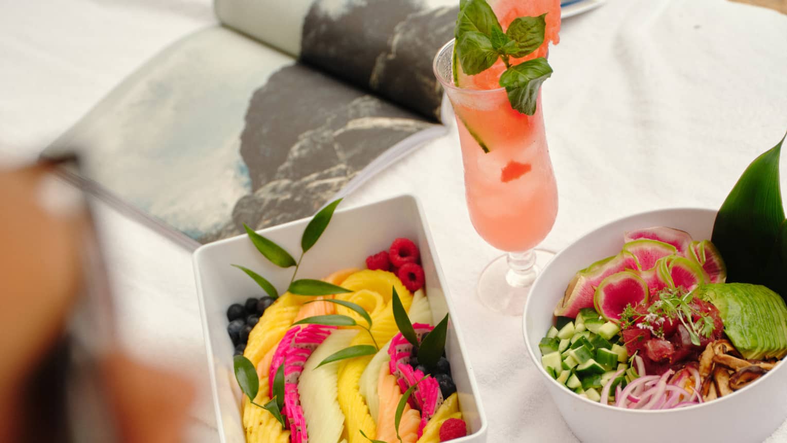 Fresh fruit and salad in white containers set on a day bed
