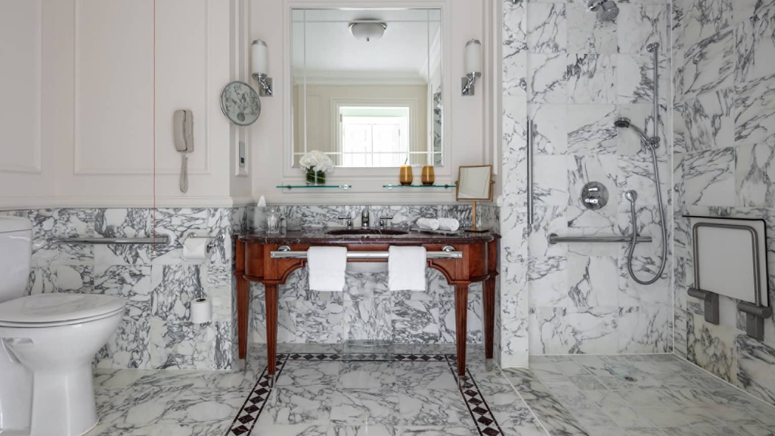 Bathroom with marble shower and glass door, porcelain commode, double wooden vanity, mirror