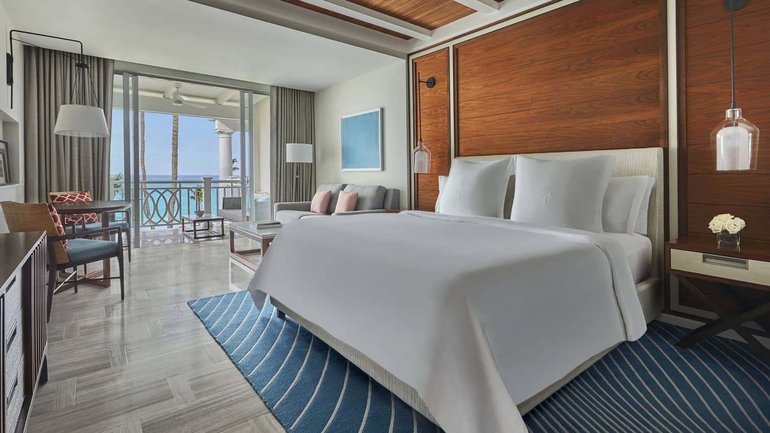Luxury ocean-view bedroom with a large bed, seating area and private balcony