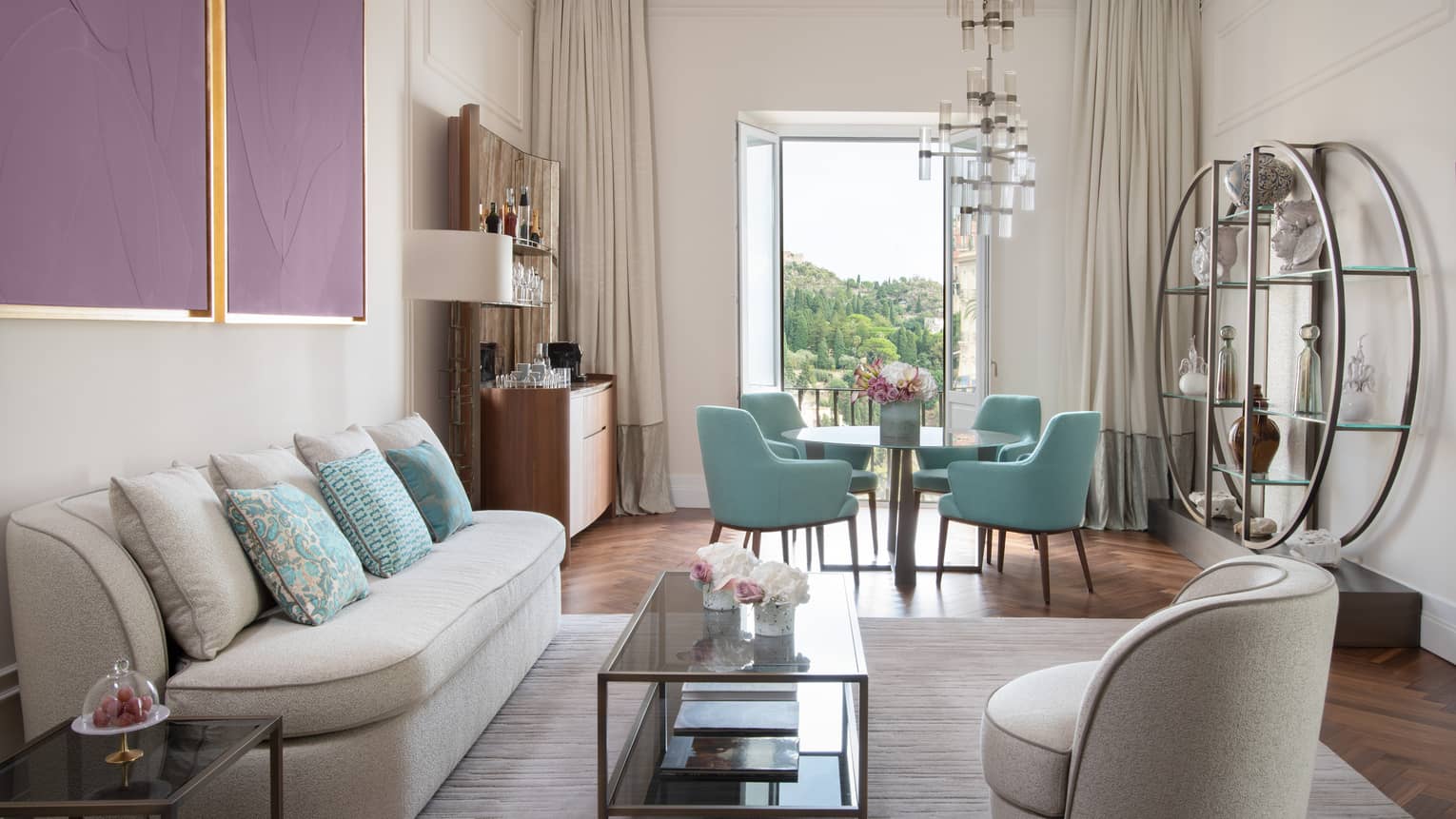 Living room with cream coloured, curved sofa, matching chair, four turquoise dining chairs