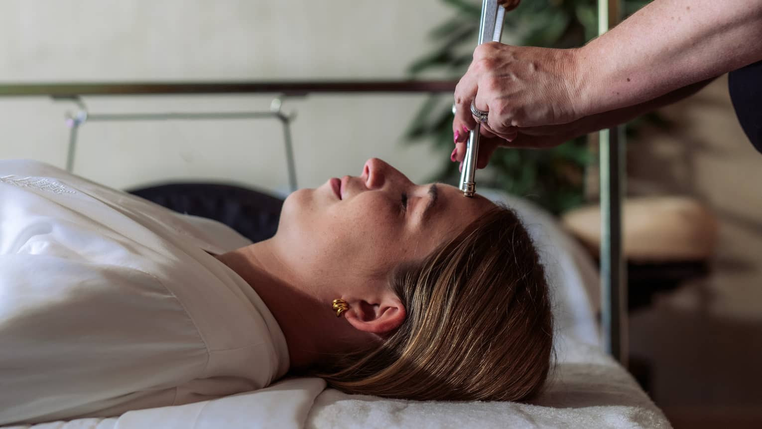 A woman receiving a sound healing treatment at a spa.