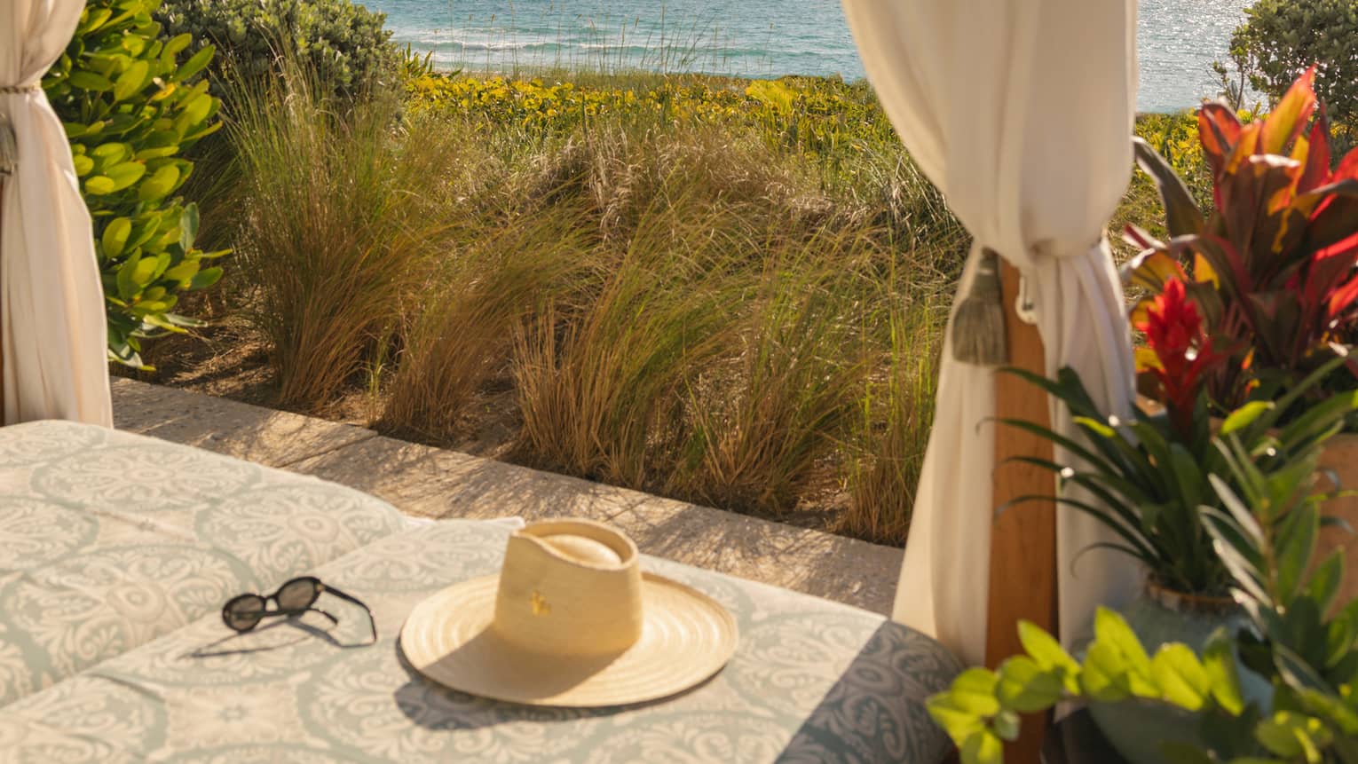 Beachside cabana overlooking the ocean with a hat lying on the cushion