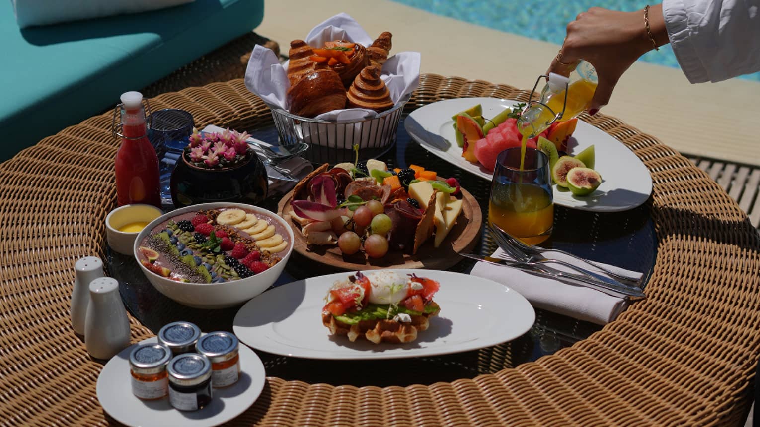 Spread of breakfast food set on an outdoor table by a pool