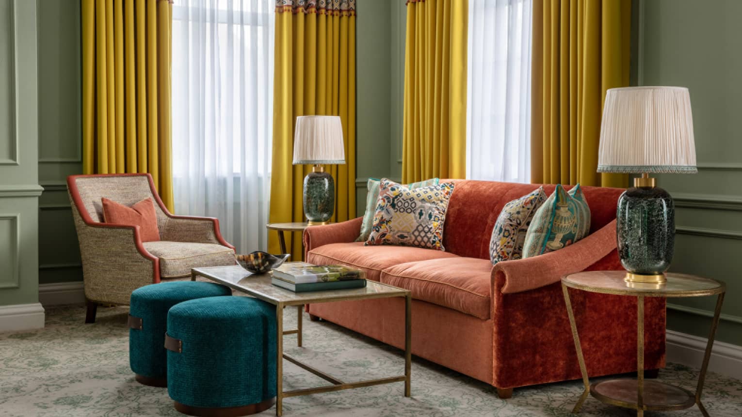 Guest room with red couch, tan accent chair, coffee table and matching end tables, twin windows with yellow drapes