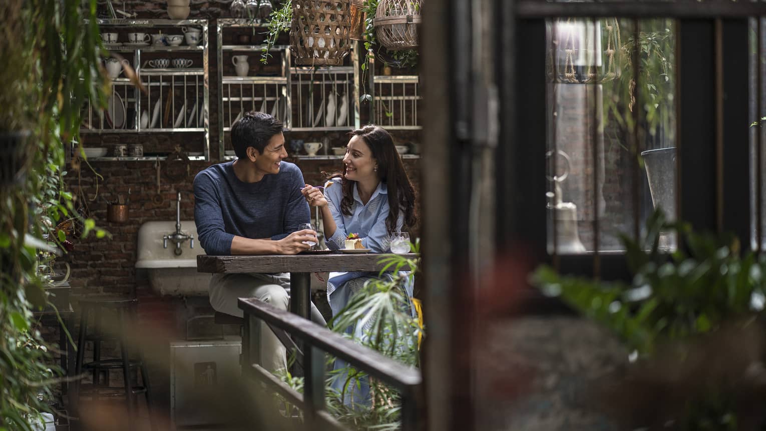 Couple enjoys cocktails and slice of cake in rustic garden lounge