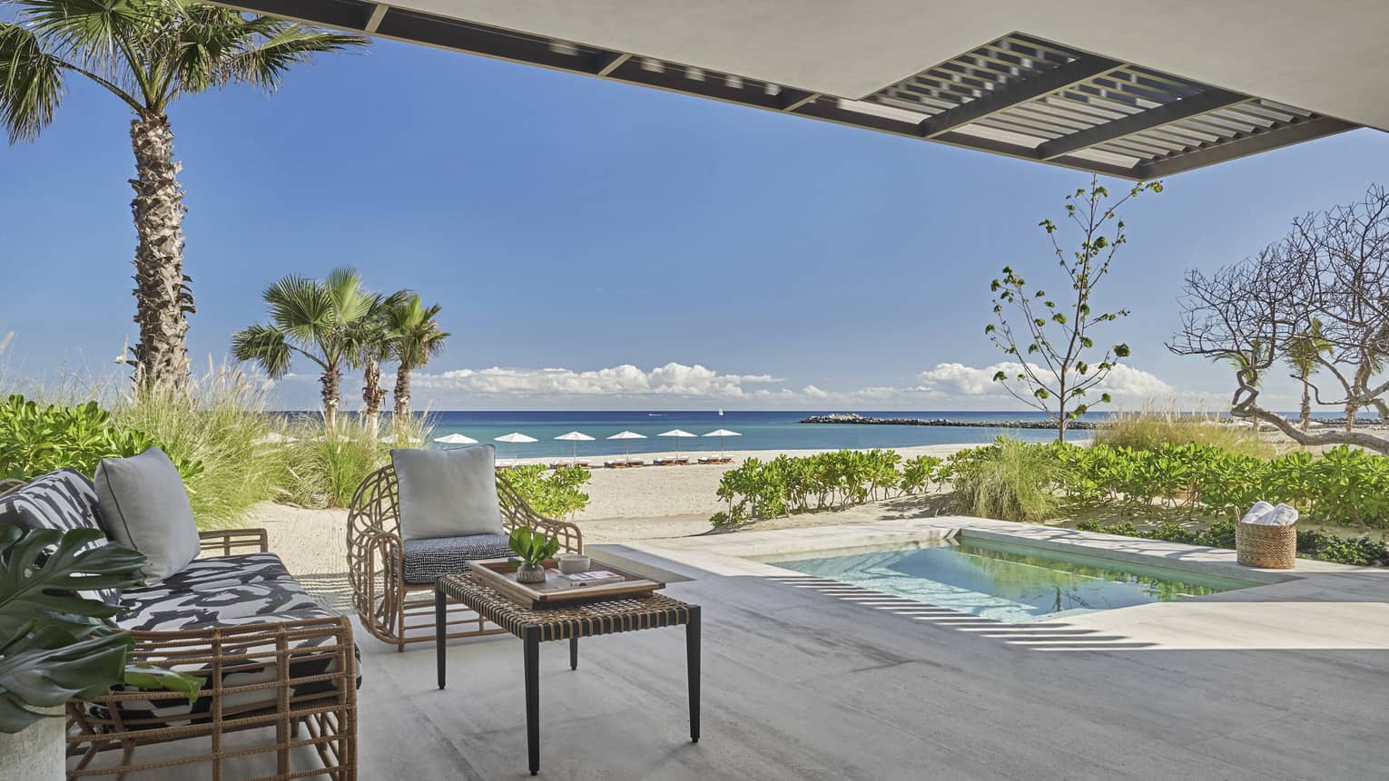 Outdoor terrace with beach and ocean view, small pool, two arm chairs and table
