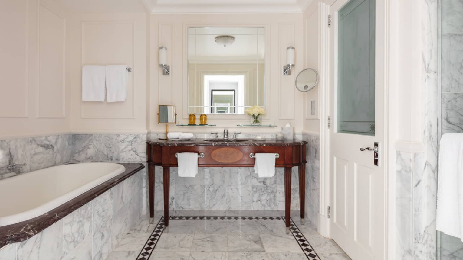 Bathroom with marble accents, large soaking tub, double wooden vanity, mirror