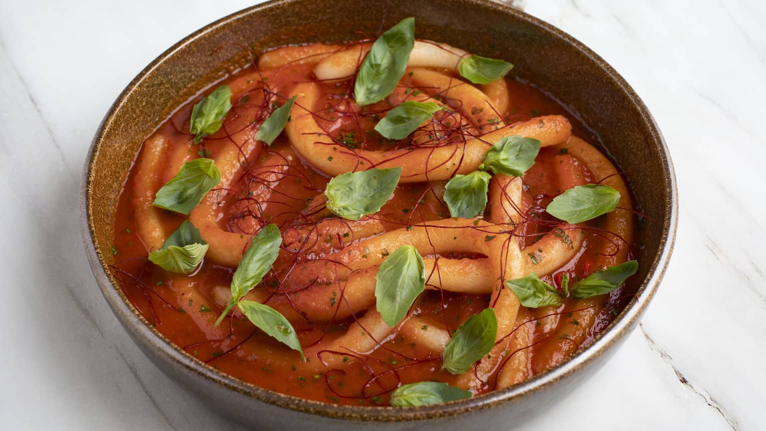 Handmade potato pici, chili, garlic, tomato sauce, fresh basil, grated Parmesan and chili thread served in a bworn stoneware bowl