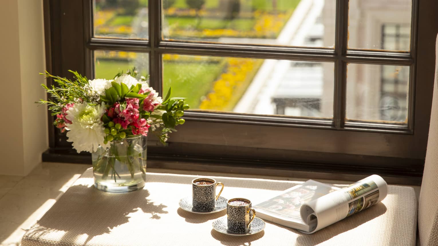 A tray of Turkish coffee, a newspaper and fresh flowers on the windowsill of a guest room, overlooking the city