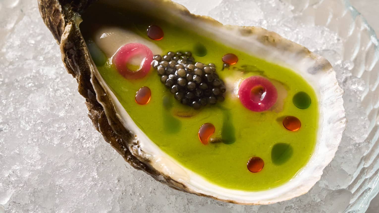 An oyster shell with green dressing and caviar
