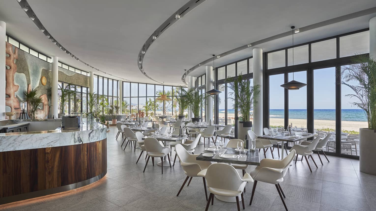 Milos contemporary curved dining room with square tables and white chairs, water views